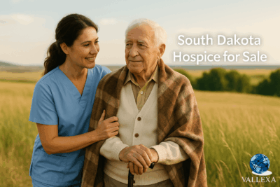 A compassionate hospice nurse supports an elderly man in a sunny South Dakota field, symbolizing end-of-life care. Text overlay reads: “South Dakota Hospice for Sale.”